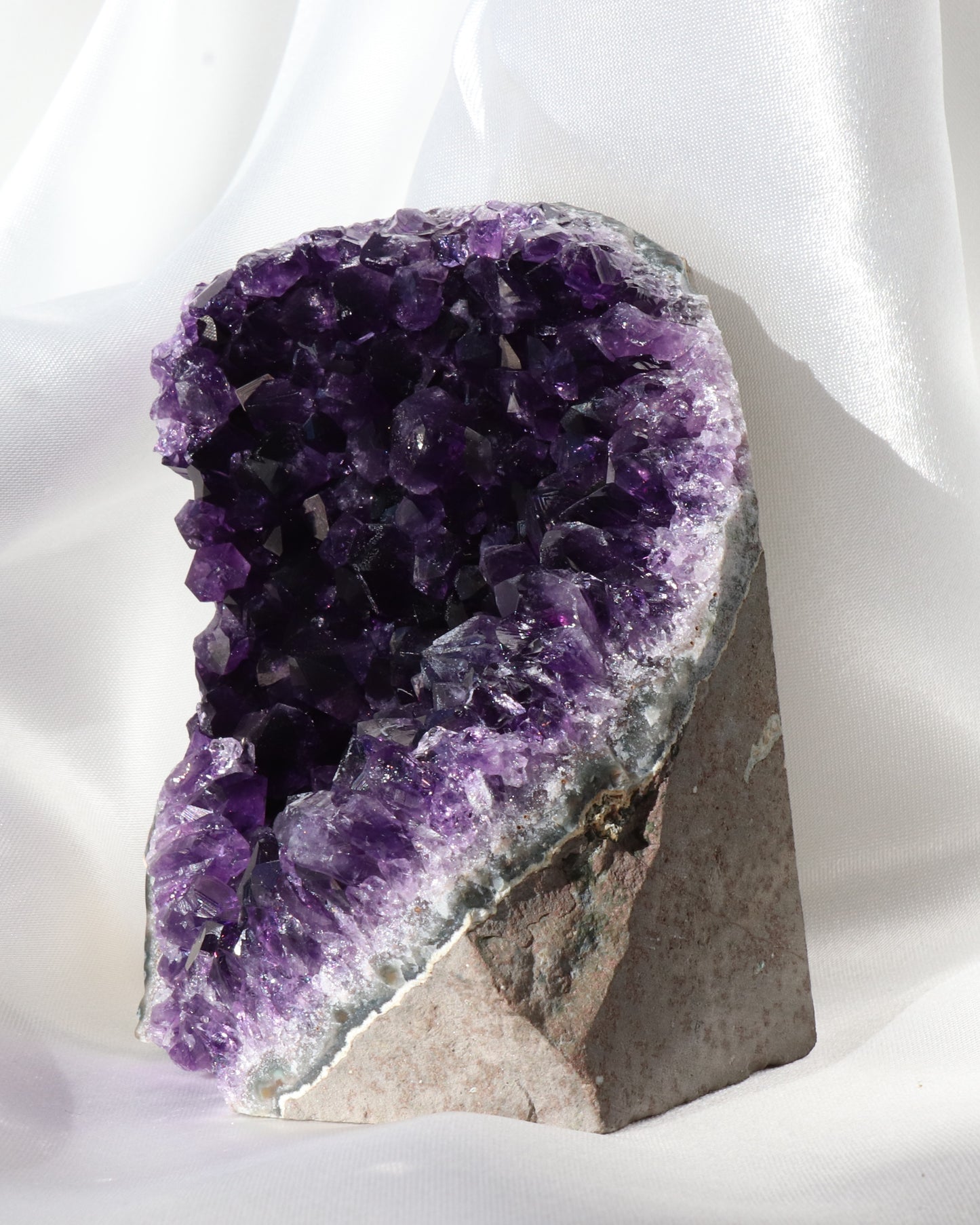 Dark purple amethyst sculpture with raw points, photo taken from the side.