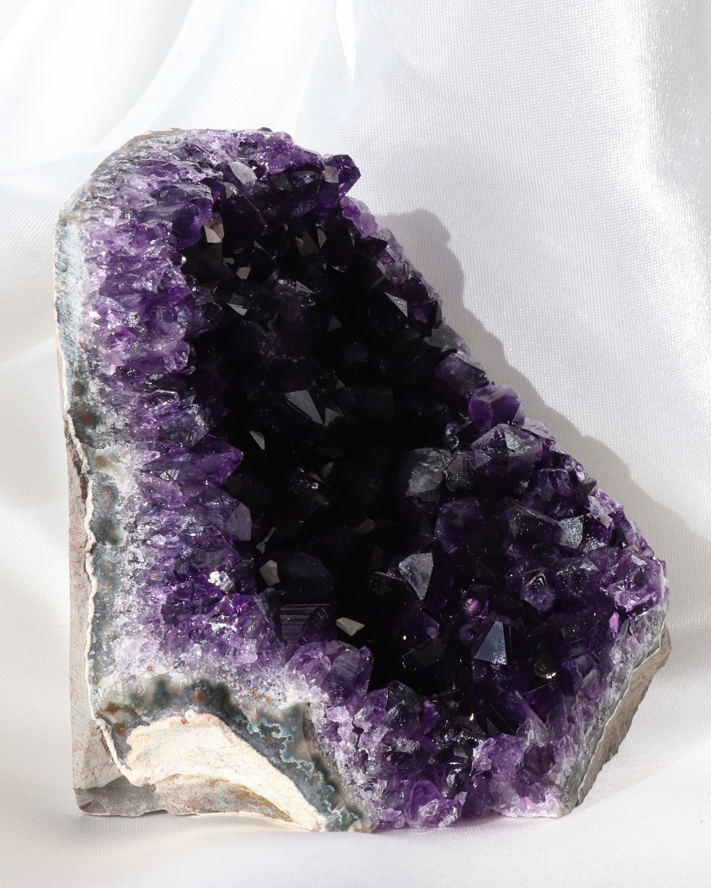 Dark purple amethyst sculpture with raw points, photo taken from the side.