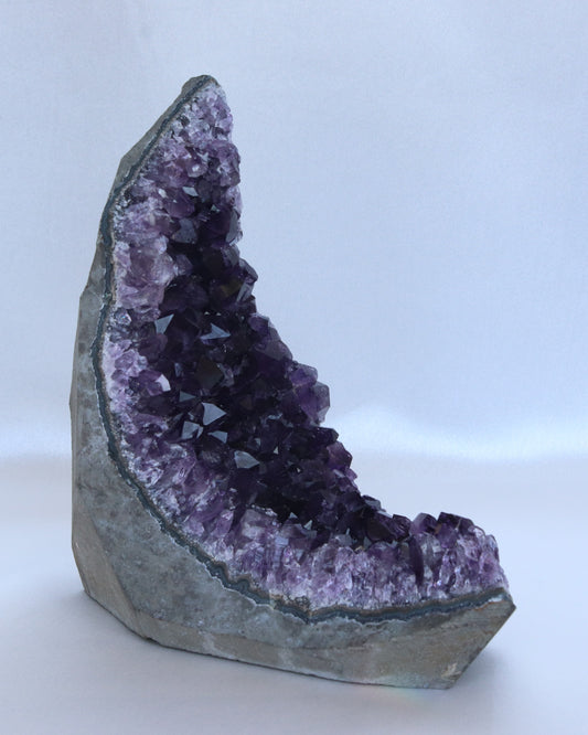 Dark purple amethyst sculpture moon shape with raw points, photo taken from the side.